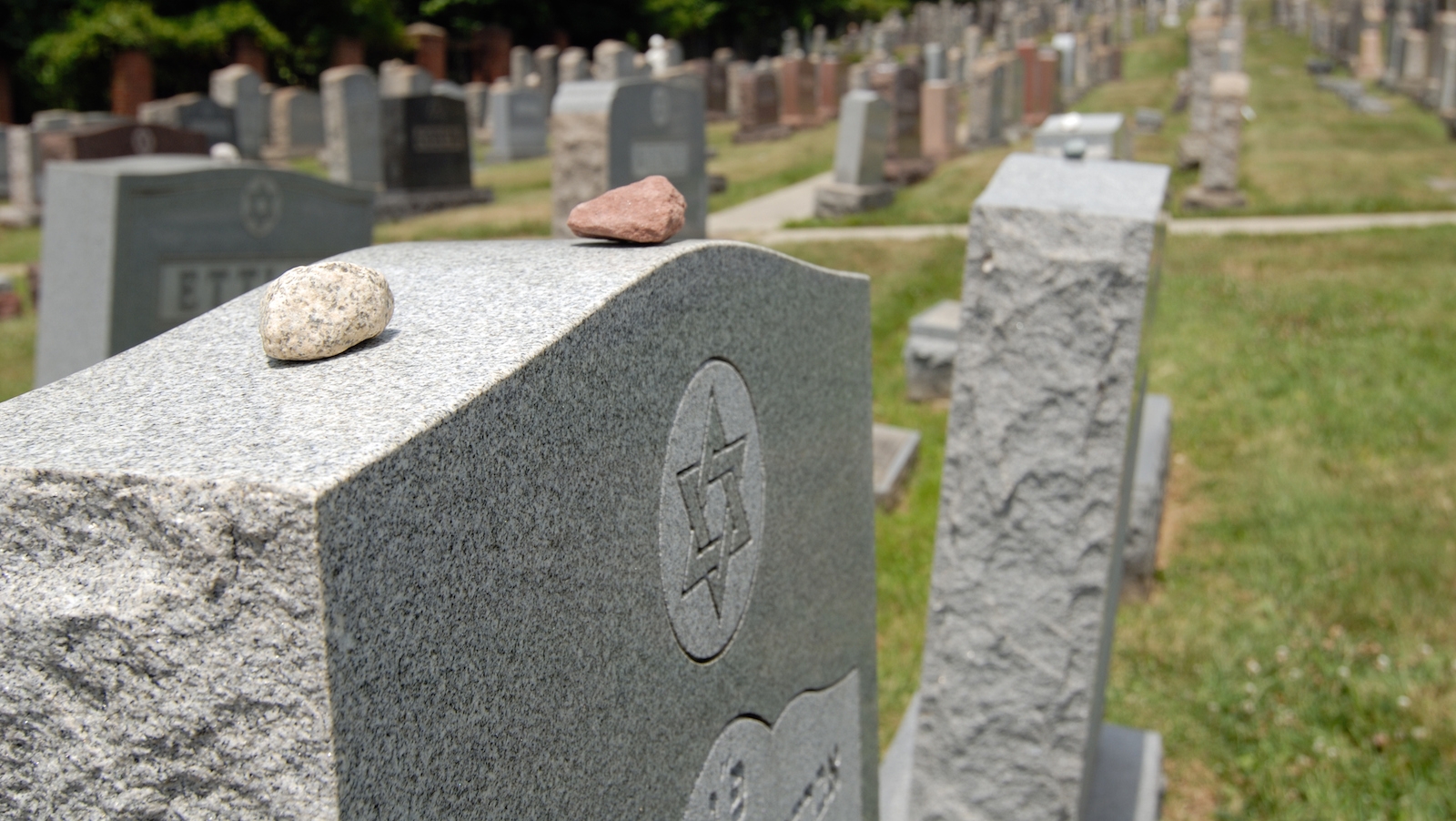why do jews place stones on a grave when they visit a cemetery and what does the custom symbolize