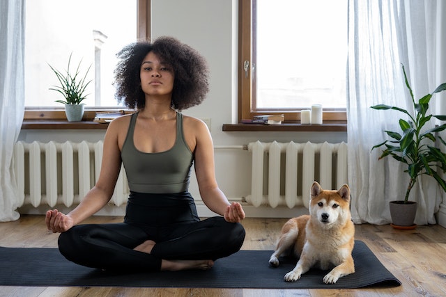 a woman practicing yoga with her dog